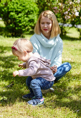 Fototapeta premium Mom and daughter on nature walk at spring park. Little girl and mother have a good time on weekend activity