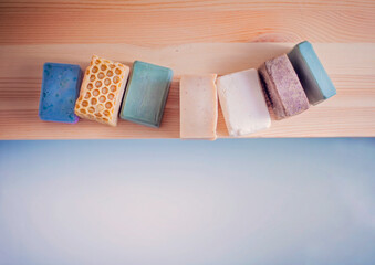 Handmade beautiful bars of organic soap displayed beside a luxurious hot bath.