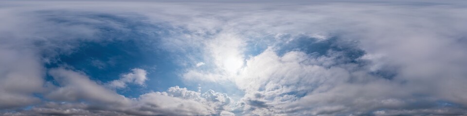 Blue evening sky seamless panorama spherical equirectangular 360 degree view with Cumulus clouds, setting sun. Full zenith for use in 3D graphics, game and aerial drone panoramas as sky replacement.