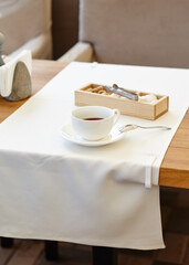 Hot coffee in a cup on wooden table. Modern design interior, restaurant blur background with bokeh image