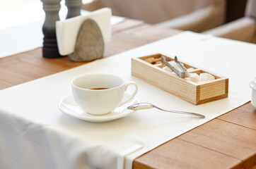 Hot coffee in a cup on wooden table. Modern design interior, restaurant blur background with bokeh image