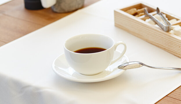 Hot coffee in a cup on wooden table. Modern design interior, restaurant blur background with bokeh image