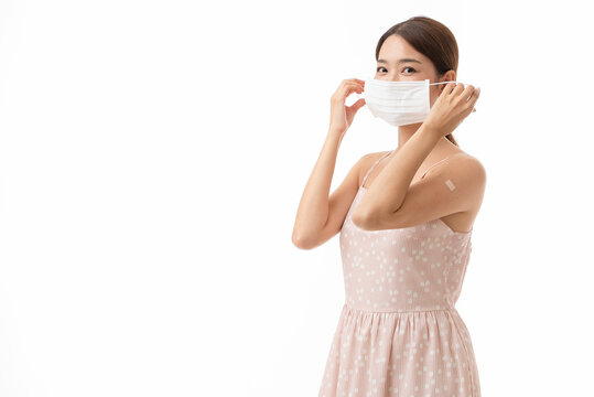 Young Asian Woman Removing Facemask After Receiving Covid-19 Vaccine, Covid-19 Vaccination Concept, Isolated On White Background