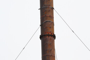 High iron pipe, photographed from the bottom up. High metal pipe with cable routes against sky....