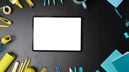 Mock up digital tablet with blank screen surrounded office supplies.