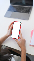 Above view of businesswoman sitting at office desk and using smart phone.