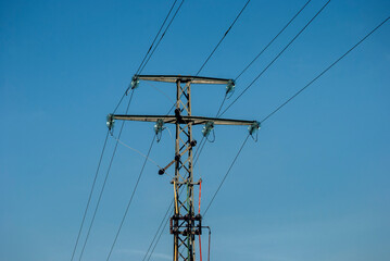 High voltage electric pole and transmission lines on clear blue sky background