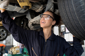 Car repairs. Auto services and Small business. A female mechanic inspecting on a car in an auto...