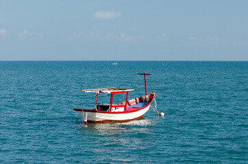 Naklejka na ściany i meble Small red boat in the water close to the beach