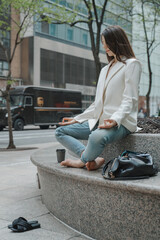 Beautiful young adult woman meditating sitting crossed leg lotus pose in white jacket, blue jeans...