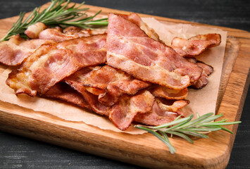 Hot fried bacon with rosemary on a black background.