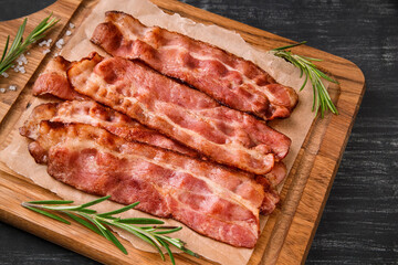 Hot fried bacon with rosemary on a black background.