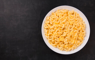 Macaroni and cheese on a white plate on a black background