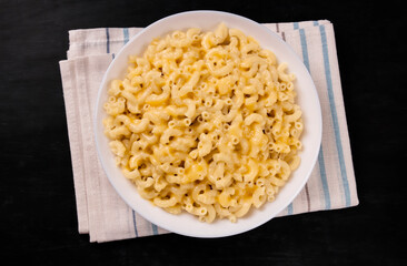 Macaroni and cheese on a white plate on a black background