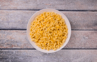 Macaroni and cheese on a white plate on a wooden background