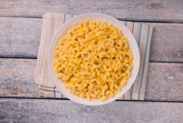 Macaroni and cheese on a white plate on a wooden background