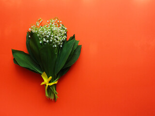 Spring or summer background. bouquet of lilies of the valley on a red background. view from above. copy space. spring flowers concept. Bright wallpaper