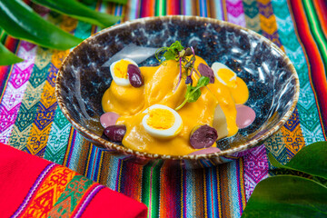 Papa a la Huancaina Peruvian boiled potatoes in hot sauce on a colorful peruvian traditional tablecloth