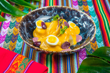 Papa a la Huancaina Peruvian boiled potatoes in hot sauce on a colorful peruvian traditional tablecloth