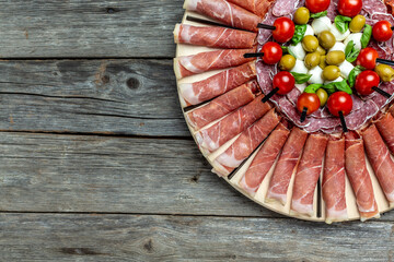 Antipasto platter. different kinds of cheese and ham, prosciutto, jamon salami on wooden vintage table, caprese snacks, aperitivo party concept. catering banner, menu, recipe