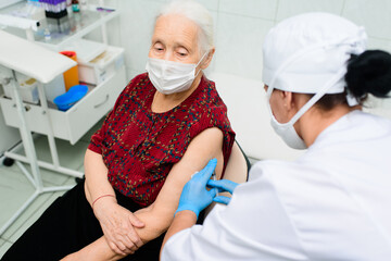a doctor or nurse injects a drug or vaccine into an elderly woman's shoulder. Vaccination against covid-19, diabetes, insulin.