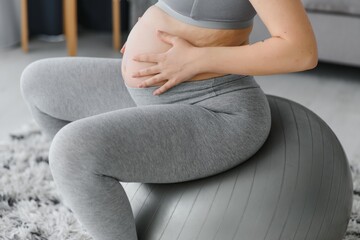 Young pregnant woman exercising yoga with fit ball at home. Healthy sports pregnancy concept