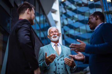 Three business men talking. Focus is on senior man.