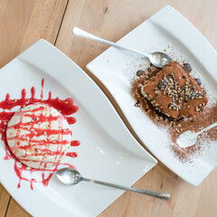 Panna cotta dessert elegantly served on a plate ready for serving, next to a tiramisu dessert. Italian traditional food.