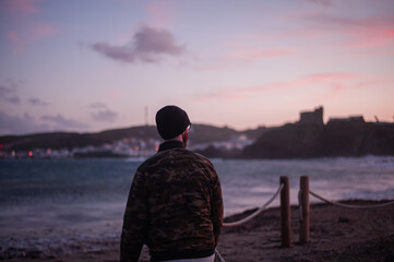 man by the sea taking pickture of the sunset with his phone