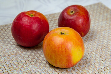 Three ripe apples on a beige wicker mat