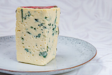 A large piece of white cheese with blue mold on a gray plate