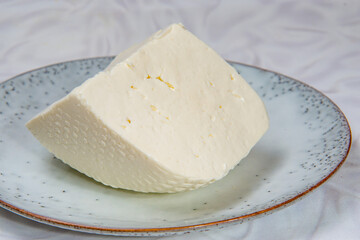 Big piece of white cheese on the grey round plate