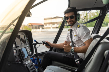 Young pilot is getting in his helicopter and preparing to take off. He is in his uniform and wearing sun glass.