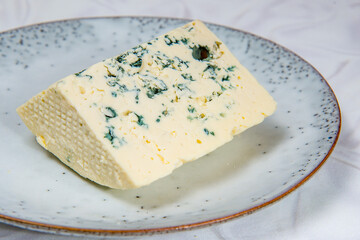 A large piece of white cheese with blue mold on a gray plate