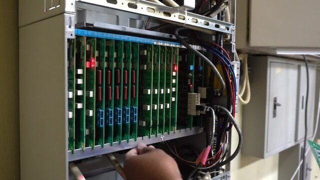 Technician or engineer changes the motherboard, PBX, telephone with flashing lights indicating the digital system connection