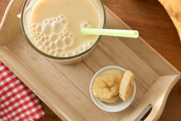 Banana drink with milk in glass on tray top detail