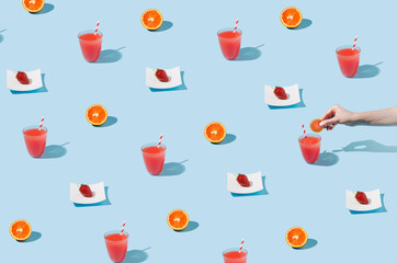 Colorful pattern made of juice, orange, and strawberry on a pastel blue background. Creative, morning layout.