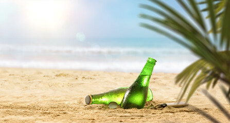 Fresh beer bottles in sand on a beach with palm