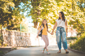  Little school girl walking with mom trough nature.