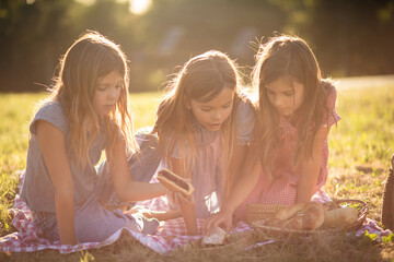 Three little girls having picnic in nature.
