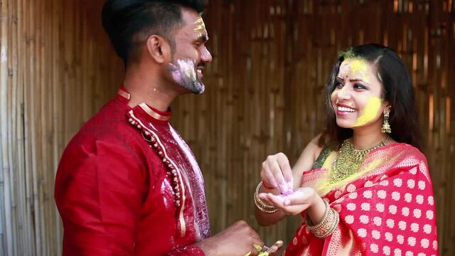 Beautiful Indian couple in ethnic dresses playing Holi and putting colors on the face