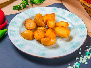 Country Style Fried Young Potato Halves On A Pale Blue Plate Which Stands On Black Stone Tray