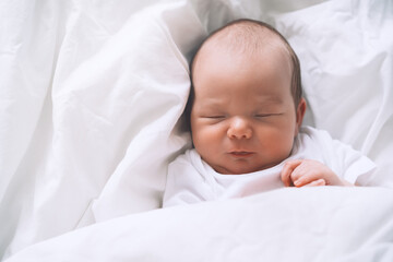Newborn sleep at first days of life. Portrait of new born baby one week old in crib in cloth background.