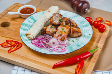 Grilled Pork Shish Kebab With Lavash Bread Sliced Onion And Hot Sauce On A Pale Blue Plate