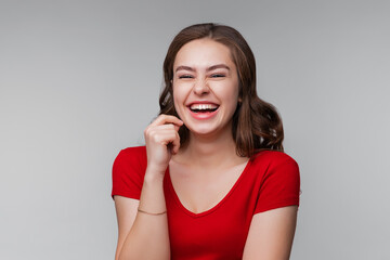 Happy cheerful young brunette woman at positive news or birthday gift, looking at camera with joyful and charming smile