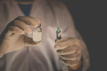 Doctor filling syringe from vial and hands with medication, closeup. Vaccination and immunization injection.selective focus,vintage color