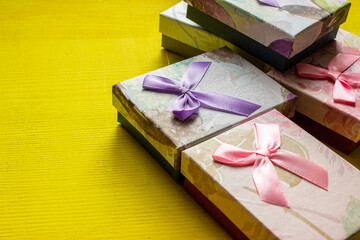 yellow long rectangular box for jewelry and bracelets with gold ribbon and small bow and white pillow on background close up 