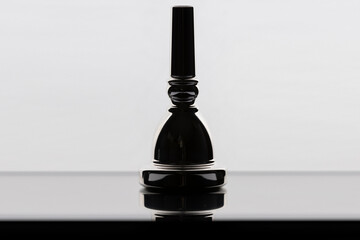 A silhouette of a tuba mouthpiece on a reflective surface with a white background