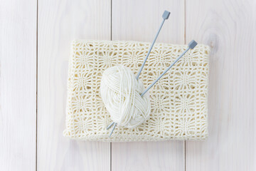 A skein of thread with knitting needles and a cloth on a wooden table. Horizontal orientation, top...