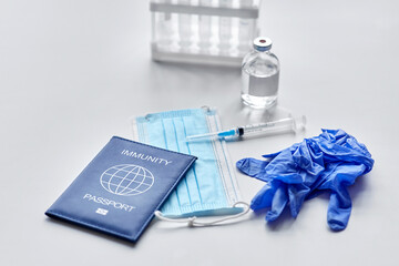 medicine, vaccination and healthcare concept - immunity passport with mask, syringe, vaccine and test tubes with protective medical gloves on white table